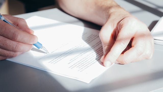 Person signing a contract with a blue pen